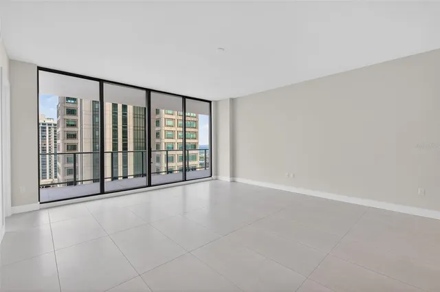 an empty room with floor to ceiling window and an outdoor view