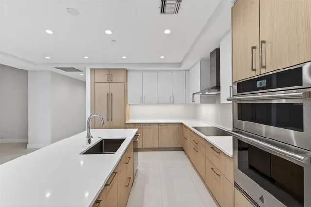 a large kitchen with stainless steel appliances a sink and a refrigerator