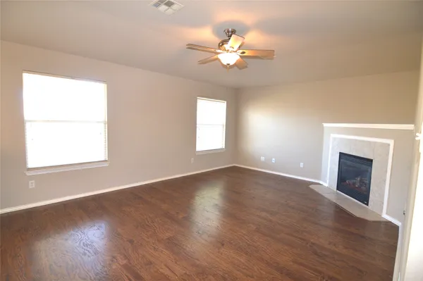 an empty room with chandelier fan and windows