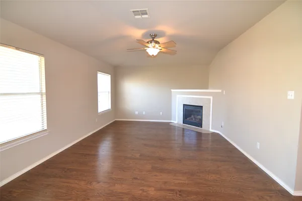 a view of a livingroom with a fireplace a ceiling fan and windows