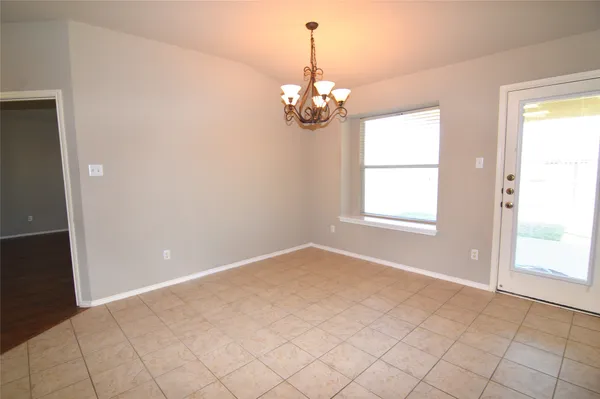 a dining hall with stainless steel appliances kitchen island granite countertop a dining table chairs and a refrigerator