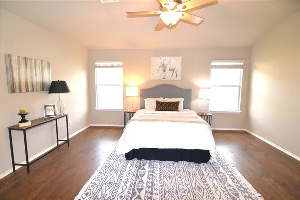an empty room with wooden floor chandelier fan and windows