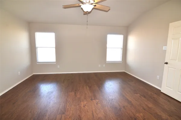 an empty room with wooden floor and fan