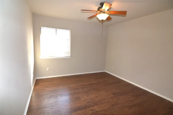 an empty room with wooden floor chandelier fan and window