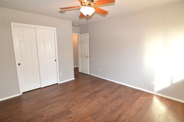 an empty room with wooden floor fan and window