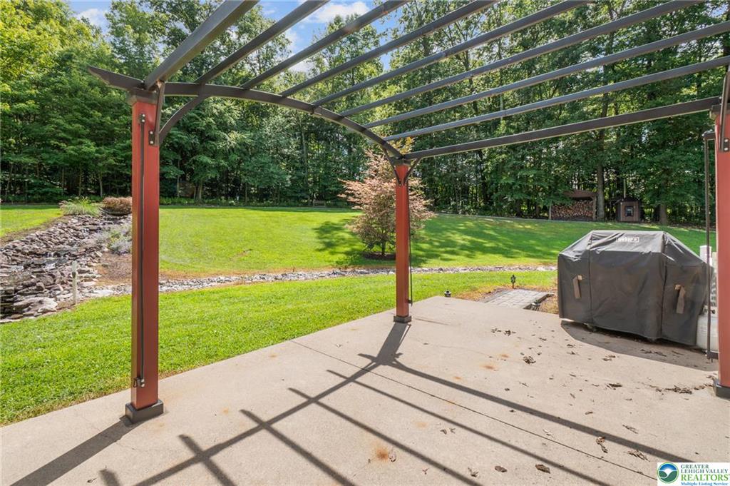 1222 Spring Road Andreas, PA 18211 - Photo 33 of 44 An open concrete patio under a
curved metal pergola looks out over
a manicured lawn.