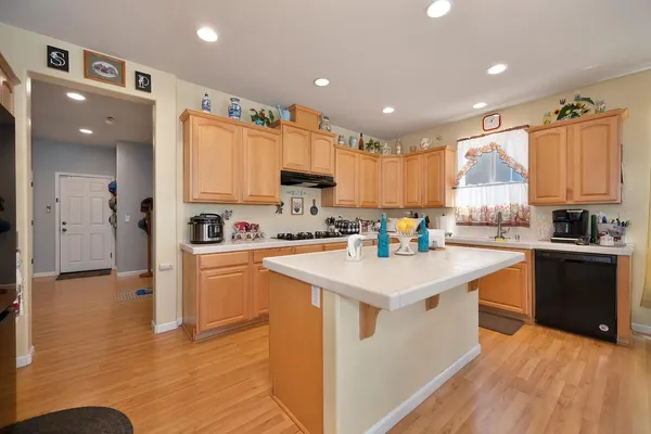 a kitchen with stainless steel appliances granite countertop a refrigerator a sink dishwasher and white cabinets with wooden floor