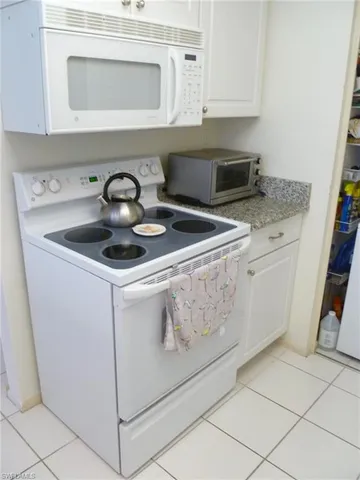 a kitchen with granite countertop white cabinets and white appliances