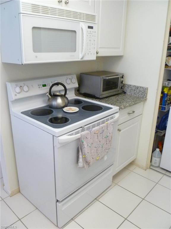 762 San Marco Road, Unit 4108 Marco Island, FL 34145 - Photo 7 of 19 a kitchen with granite countertop white cabinets and white appliances