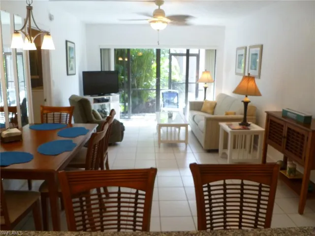a living room with furniture a flat screen tv and floor to ceiling window