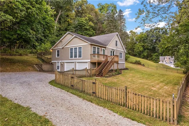 a view of a house with a small yard and large trees