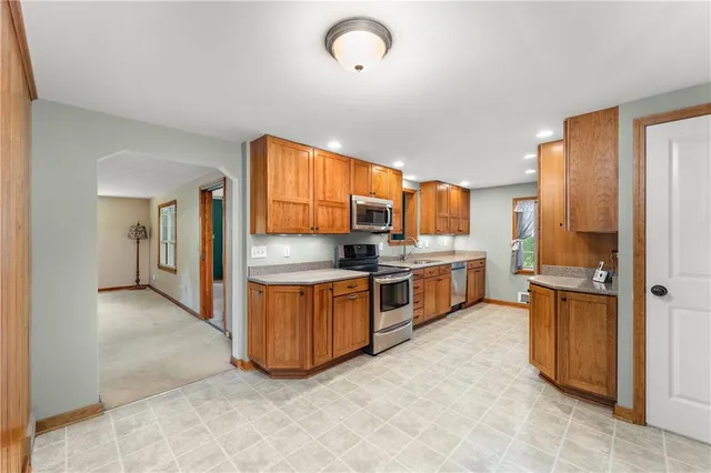 a large kitchen with stainless steel appliances granite countertop a stove refrigerator and cabinets