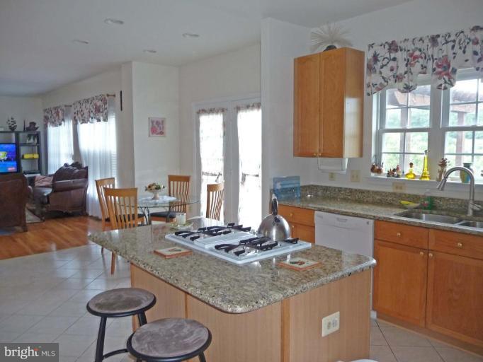 6089 Deer Ridge Trail Springfield, VA 22150 - Photo 12 of 30 a kitchen with stainless steel appliances granite countertop a sink a stove a dining table and chairs