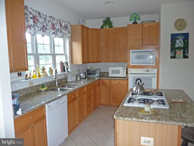 6089 Deer Ridge Trail Springfield, VA 22150 - Photo 10 of 30 a kitchen with granite countertop a sink a stove and wooden cabinets