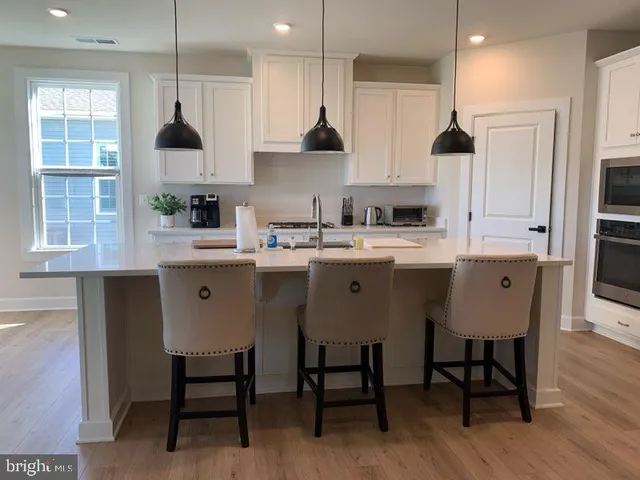 a kitchen with stainless steel appliances a sink a stove a refrigerator and island with wooden floor