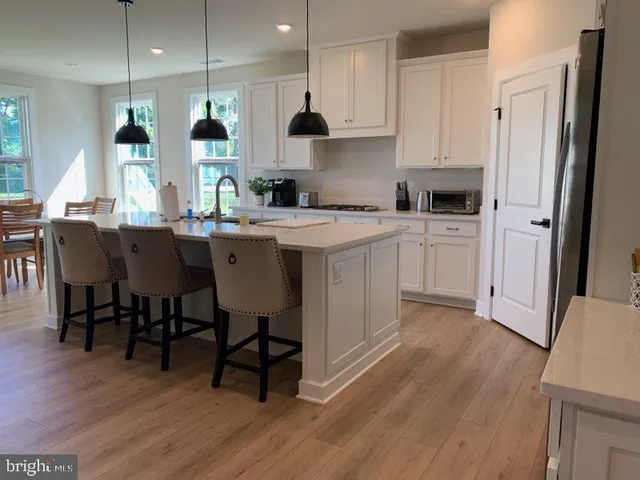 a kitchen with stainless steel appliances granite countertop a table chairs sink refrigerator and cabinets