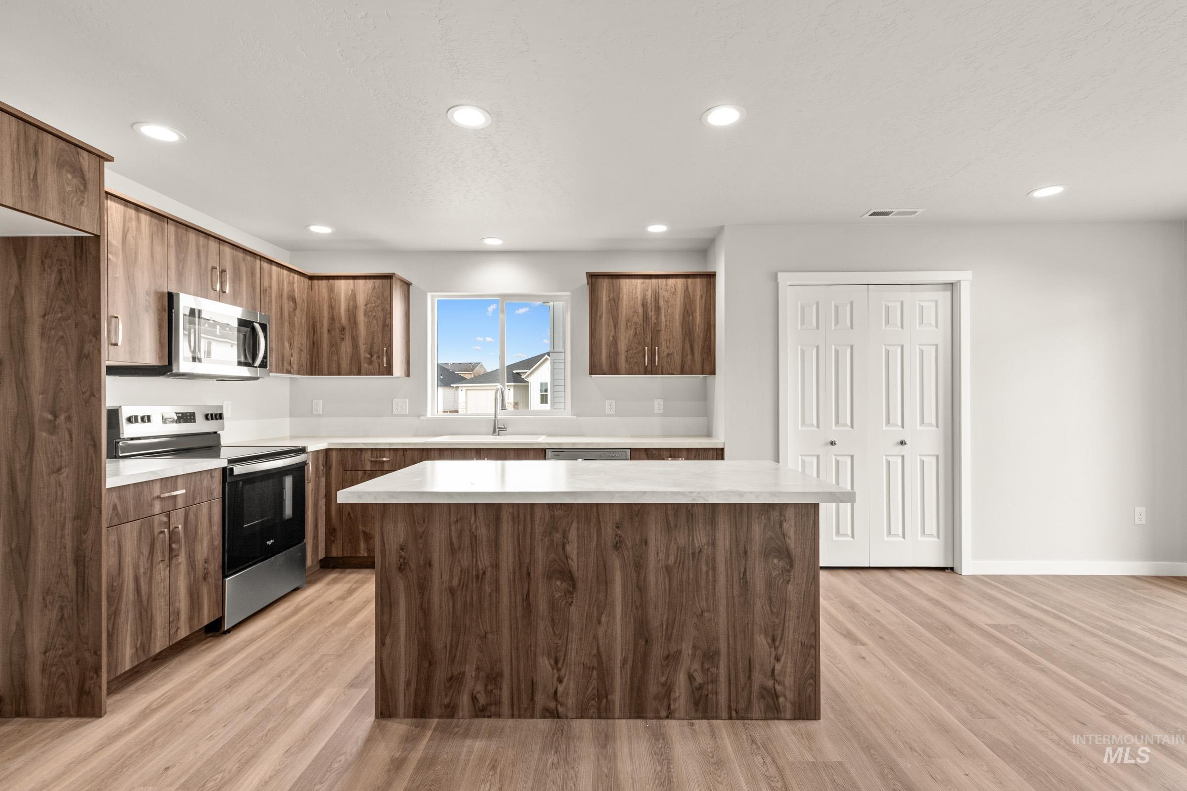 13704 Redway Court Caldwell, ID 83607 - Photo 3 of 23 Kitchen with stainless steel appliances, light countertops, light wood-type flooring, recessed lighting, and a center island