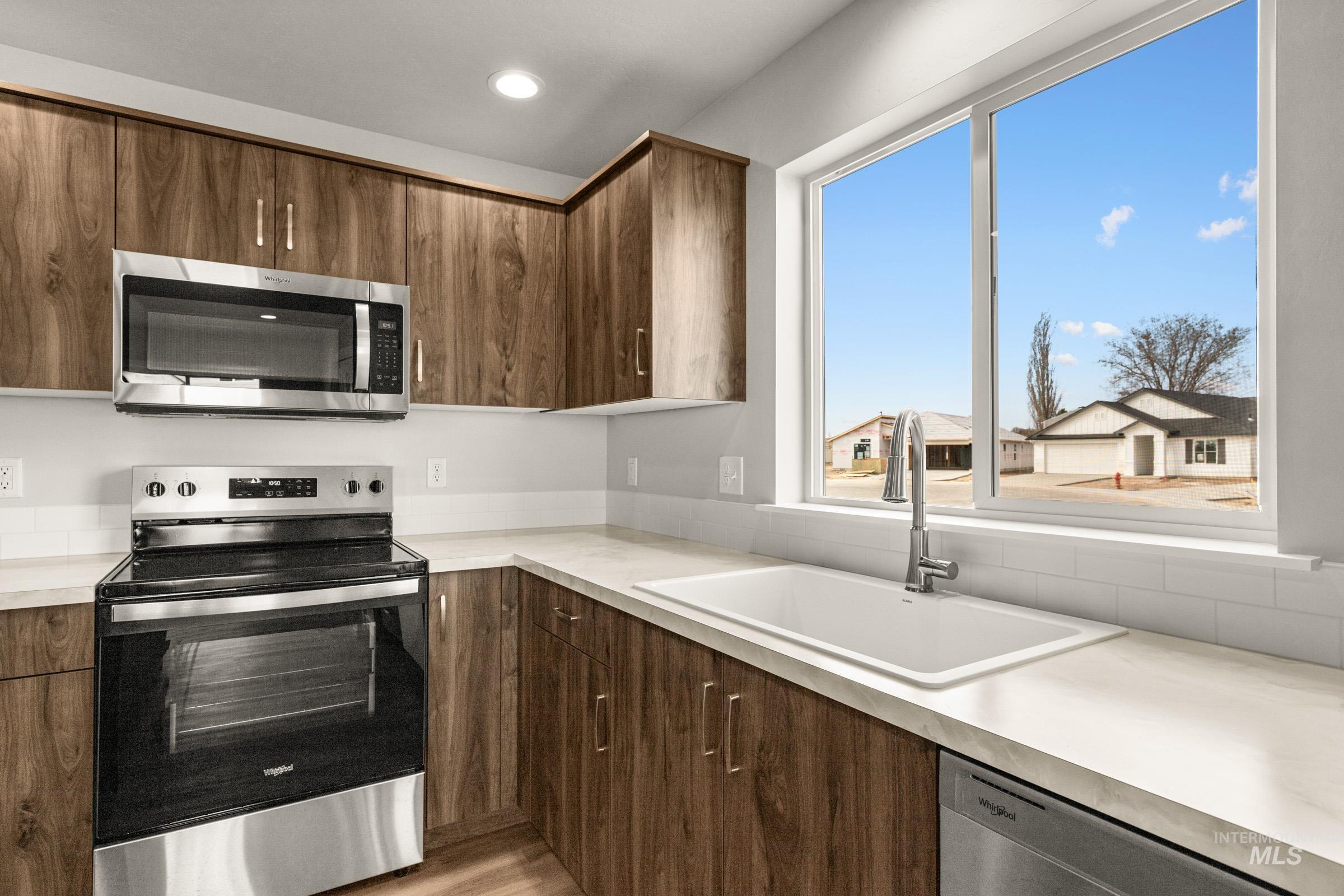 13704 Redway Court Caldwell, ID 83607 - Photo 6 of 23 Kitchen with stainless steel appliances, light countertops, and dark wood finish cabinets