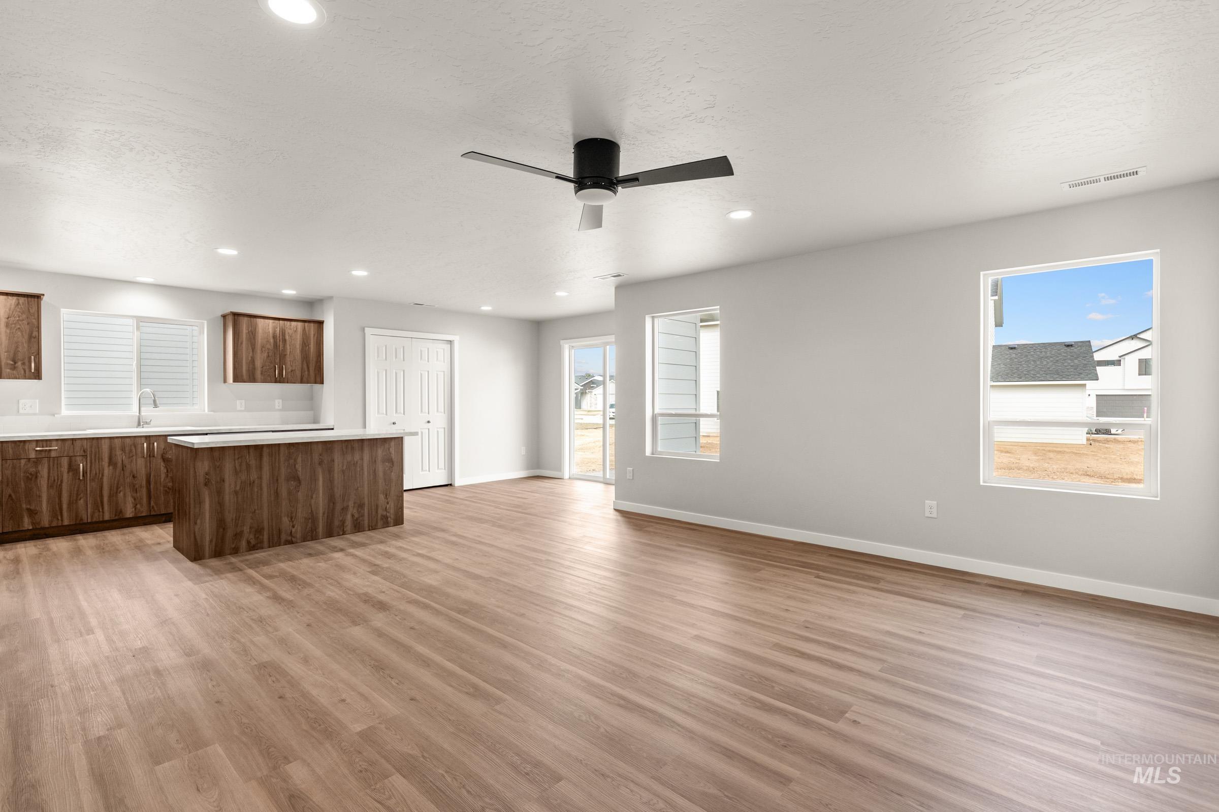 13704 Redway Court Caldwell, ID 83607 - Photo 9 of 23 Unfurnished living room featuring recessed lighting, a ceiling fan, light wood finished floors, plenty of natural light, and a textured ceiling