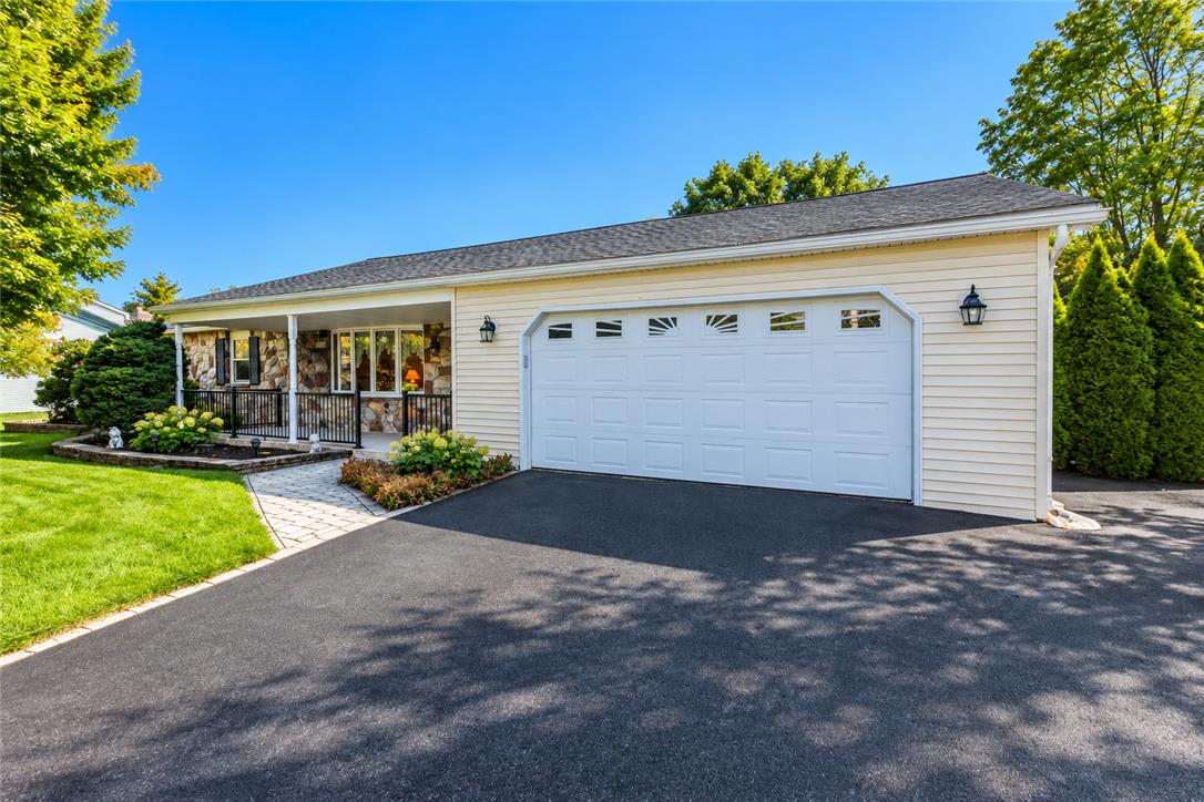 An inviting paved driveway leads directly to a spacious attached garage under a neat roofline.