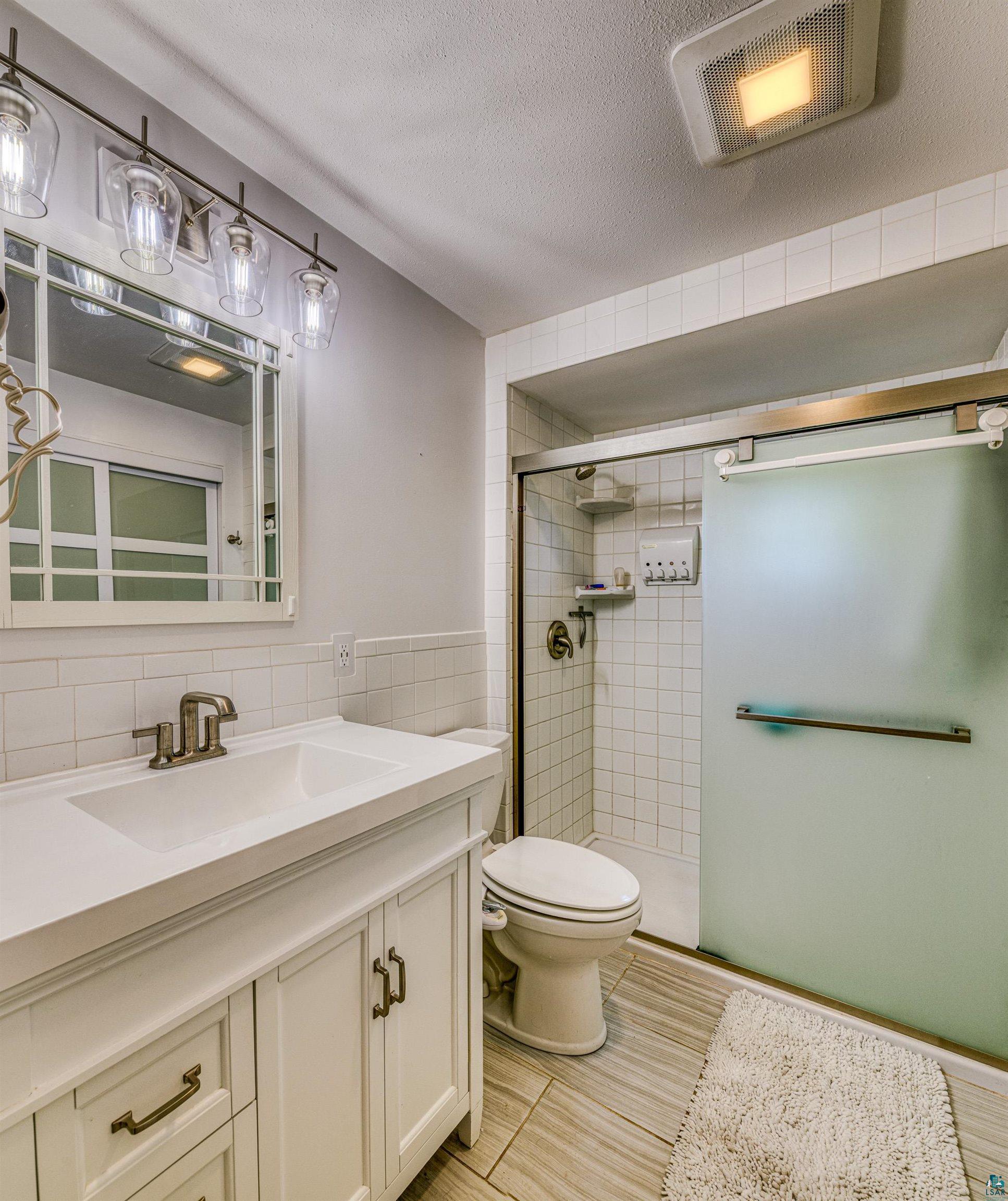 66075 Rooster Road Iron River, WI 54847 - Photo 22 of 52 Bathroom featuring a white vanity with integrated sink, bronze-finish faucet, and coordinating cabinet hardware