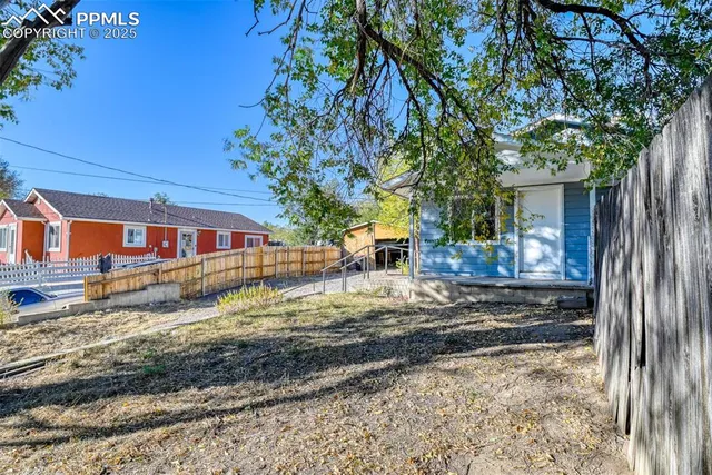 a view of a house with a yard tree and wooden fence