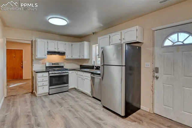 a kitchen with a refrigerator a stove top oven and wooden floor