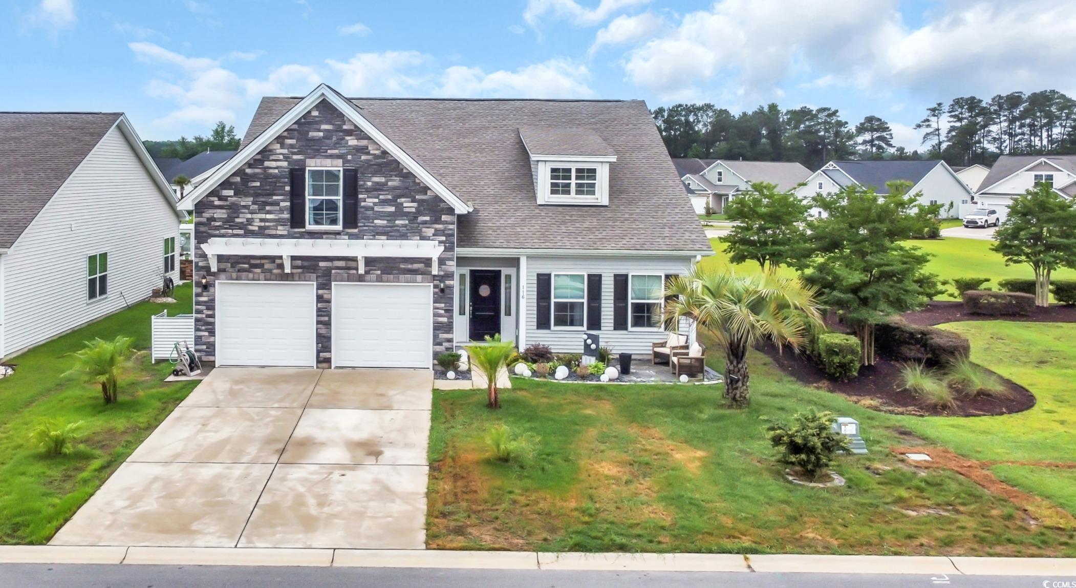 View of front of property featuring driveway, an attached garage, a front yard, and stone siding