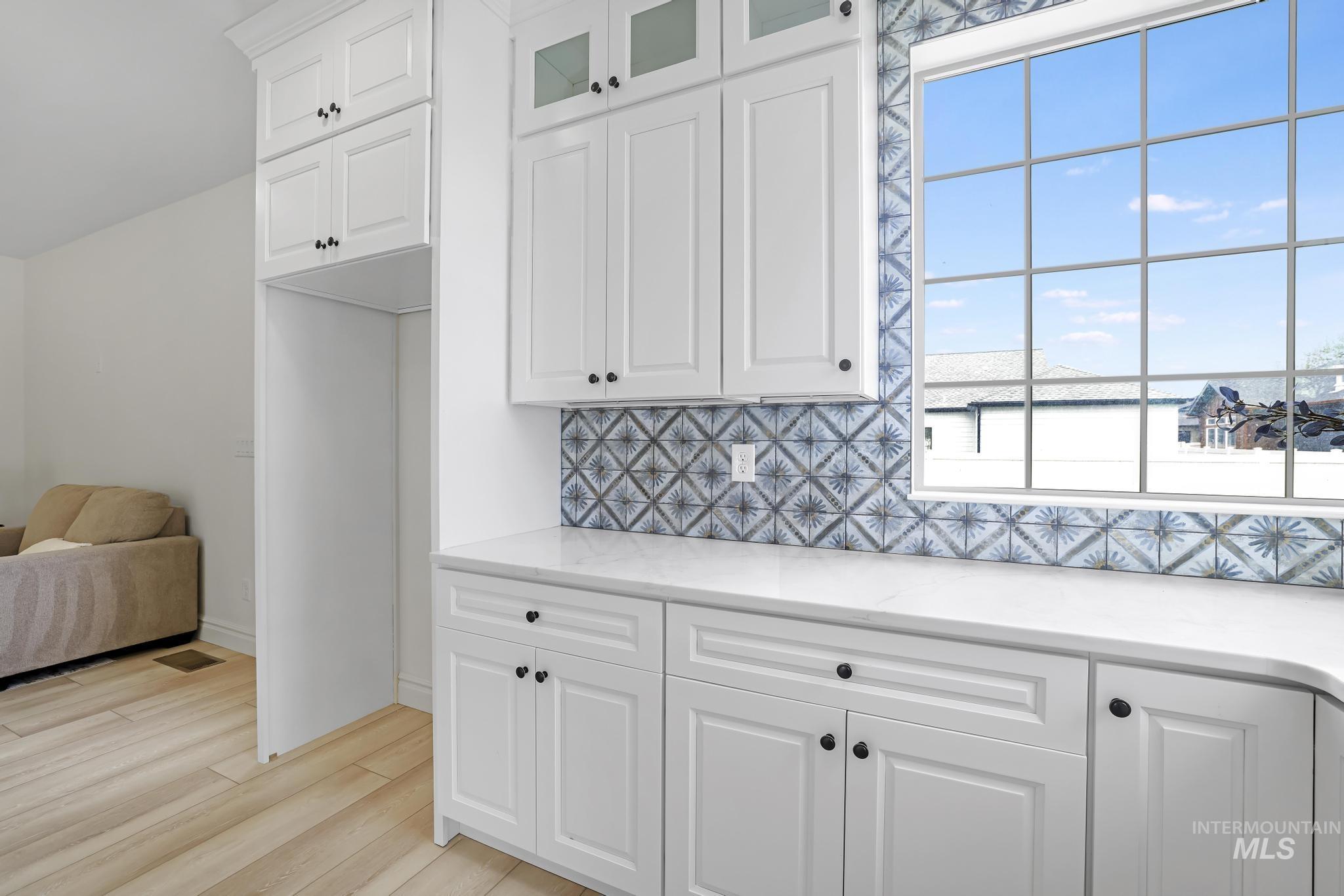 866 Quartz Road Kimberly, ID 83341 - Photo 17 of 48 White shaker cabinetry with dark hardware, a patterned tile backsplash, and light wood-finish flooring