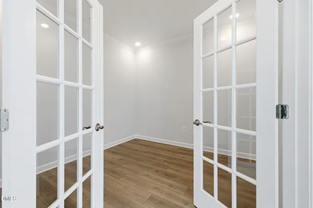 a view of an empty room with wooden floor and windows