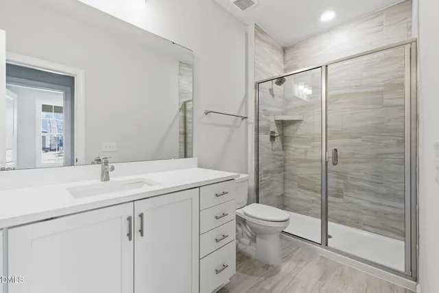 a bathroom with a shower sink vanity mirror and toilet
