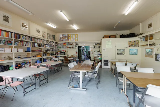 a living room with stainless steel appliances a dining table and a refrigerator