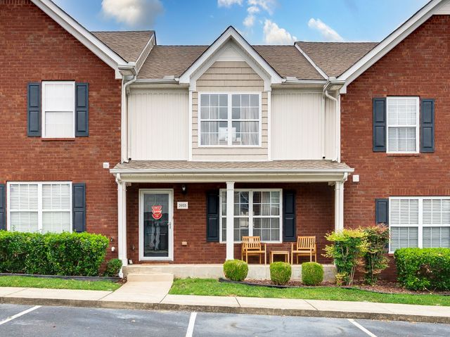 a view of a brick house with a yard plants and a large window