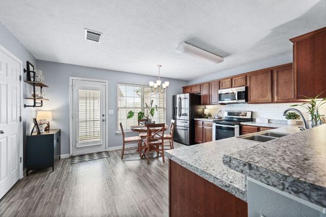 a kitchen with stainless steel appliances granite countertop a refrigerator a stove top oven a sink dishwasher and cabinets with wooden floor