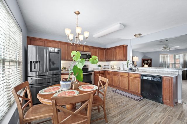a dining room with wooden floor a chandelier a wooden table and chairs