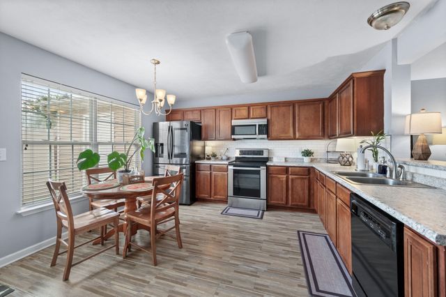 a kitchen with kitchen island granite countertop wooden floors wooden cabinets dining table and stainless steel appliances