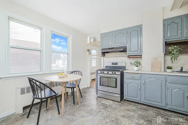 a kitchen with stainless steel appliances a stove a sink cabinets and a window