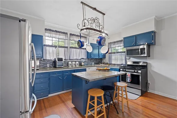 a kitchen with stainless steel appliances granite countertop a stove top oven a sink dishwasher and white cabinets with wooden floor