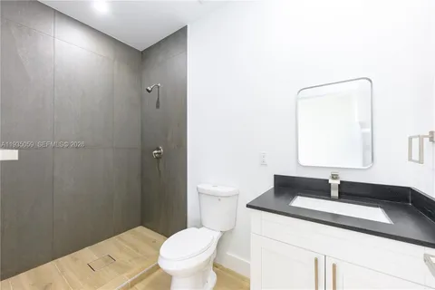 a bathroom with a granite countertop sink toilet a mirror and a shower