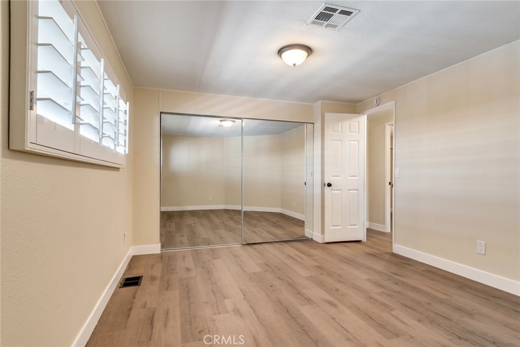 10210 Base Line Road, Unit 115 Rancho Cucamonga, CA 91701 - Photo 11 of 23 an empty room with wooden floor and windows