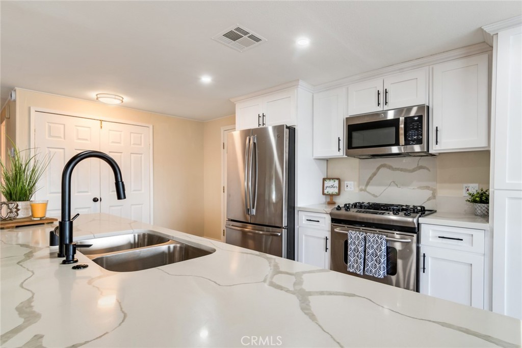 10210 Base Line Road, Unit 115 Rancho Cucamonga, CA 91701 - Photo 4 of 23 a kitchen with stainless steel appliances kitchen island a stove a sink and a microwave