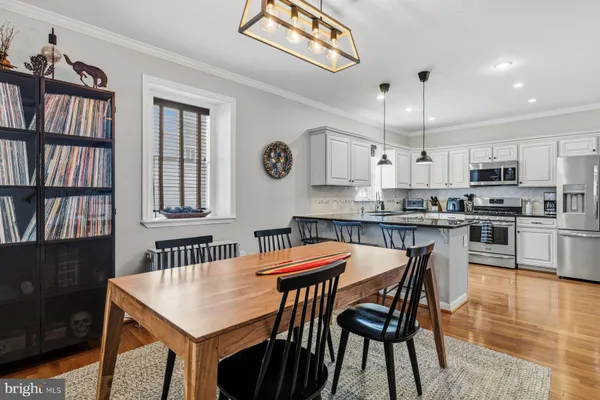 a kitchen with stainless steel appliances granite countertop a dining table chairs refrigerator and cabinets