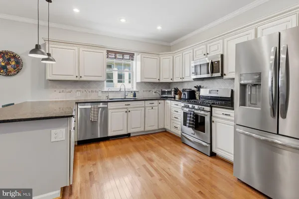 a kitchen with stainless steel appliances a sink cabinets and a wooden floor
