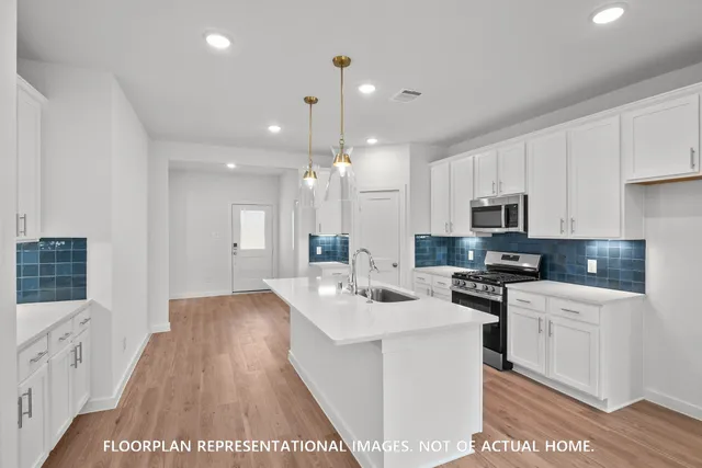 a kitchen with stainless steel appliances kitchen island a stove a sink a refrigerator and a microwave