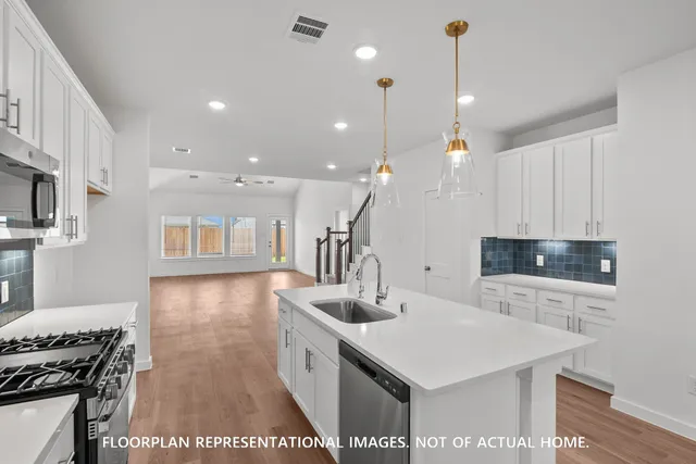a large white kitchen with kitchen island a sink white cabinets and stainless steel appliances