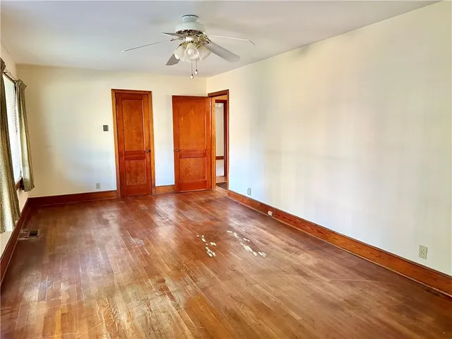 a view of an empty room with window and wooden floor