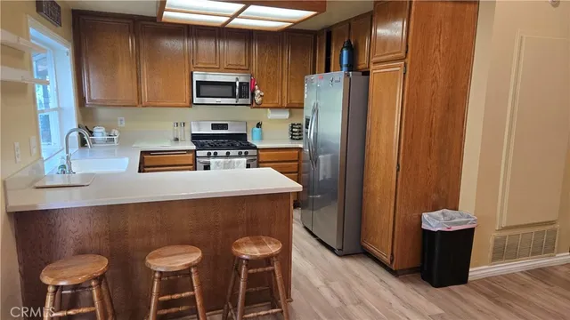 a kitchen with stainless steel appliances granite countertop a refrigerator stove top oven a sink and dishwasher with wooden floor