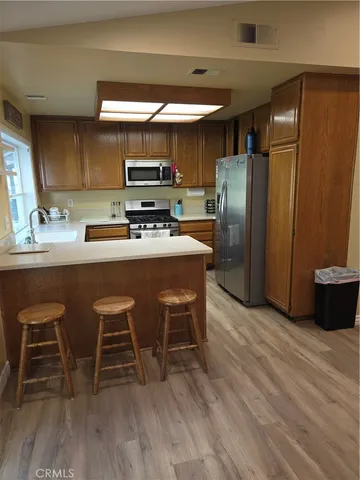 a kitchen with stainless steel appliances a dining table chairs refrigerator and sink