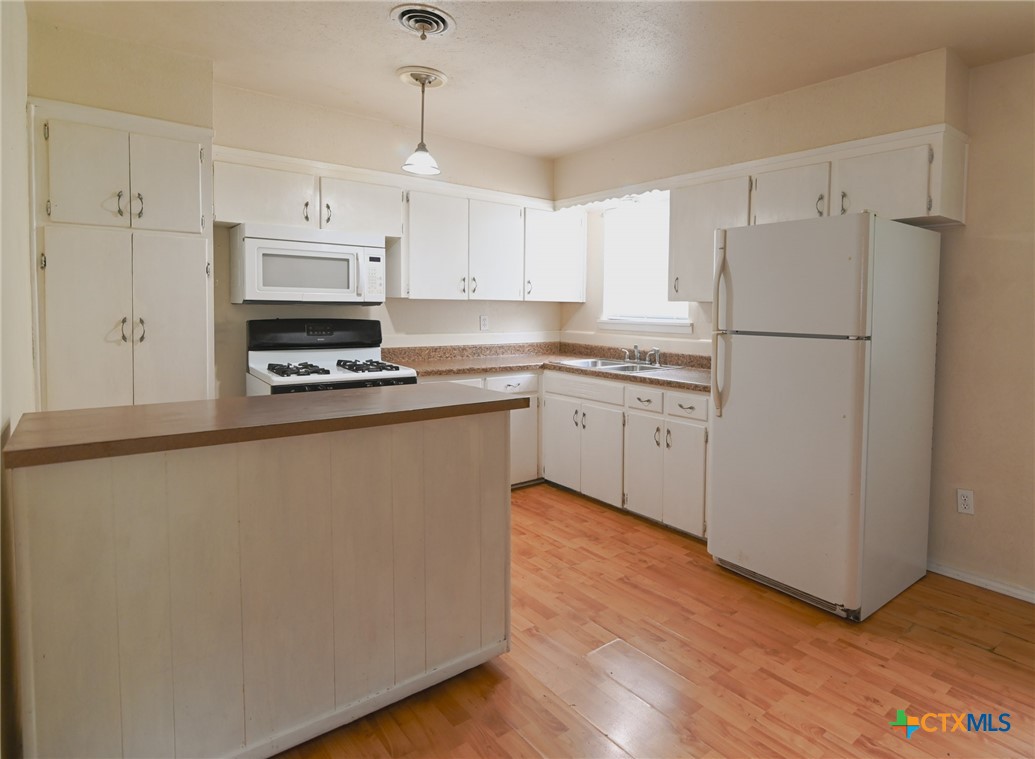 707 South 5th Street Copperas Cove, TX 76522 - Photo 11 of 19 a kitchen with kitchen island a white cabinets and refrigerator