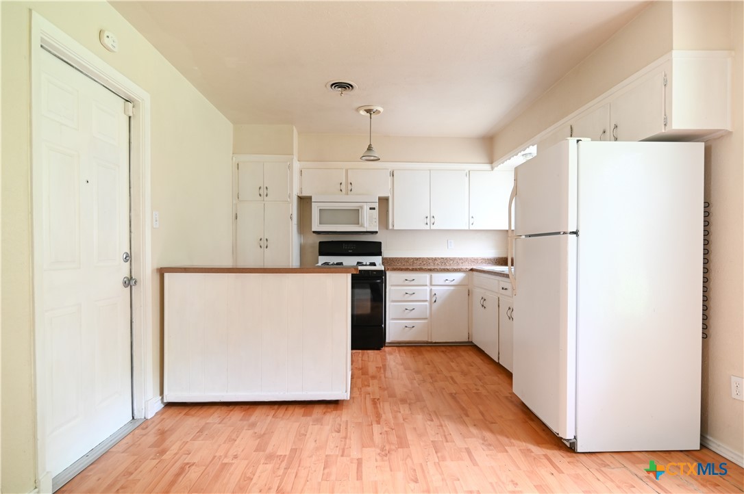 707 South 5th Street Copperas Cove, TX 76522 - Photo 10 of 19 a kitchen with a refrigerator a white stove top oven and a sink with wooden floor